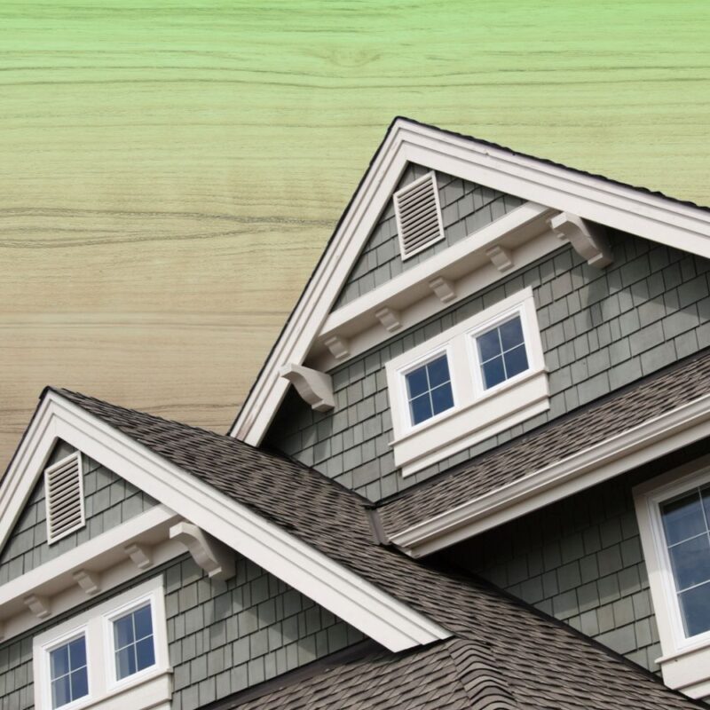 House gables with wood shake siding and asphalt roof shingles set against a natural wood grain textured background.
